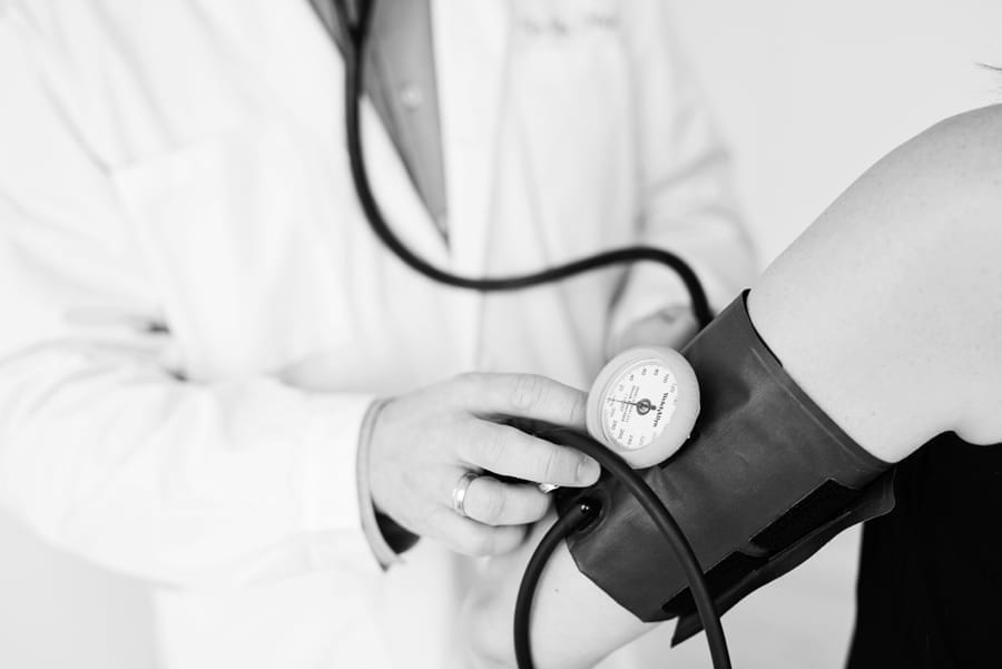 Läkare mäter blodtryck på en patient, svartvitt foto