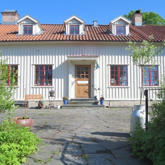 Entrén till Prästgården i Vallda med stensatt gård och röda fönster